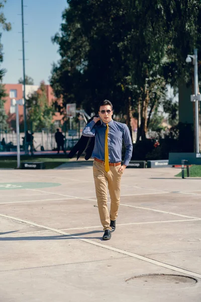 İki renkli kot pantolonlu, siyah beyaz kravatlı ve gözlüklü bir adam..