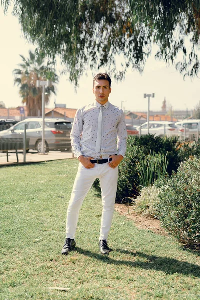 İki renkli kot pantolonlu, siyah beyaz kravatlı ve gözlüklü bir adam..