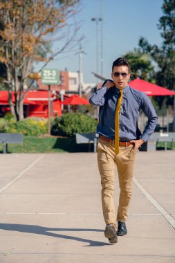 İki renkli kot pantolonlu, siyah beyaz kravatlı ve gözlüklü bir adam..