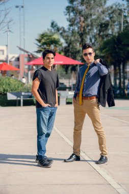 İki renkli kot pantolonlu, siyah beyaz kravatlı ve gözlüklü bir adam..