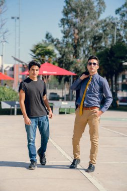 İki renkli kot pantolonlu, siyah beyaz kravatlı ve gözlüklü bir adam..