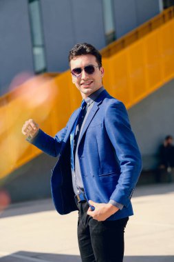 İki renkli kot pantolonlu, siyah beyaz kravatlı ve gözlüklü bir adam..