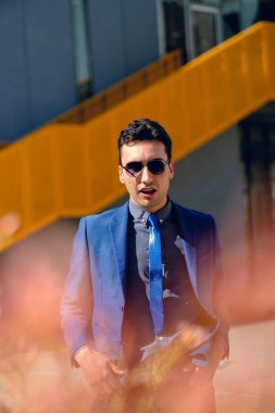 İki renkli kot pantolonlu, siyah beyaz kravatlı ve gözlüklü bir adam..