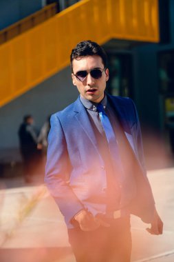 İki renkli kot pantolonlu, siyah beyaz kravatlı ve gözlüklü bir adam..