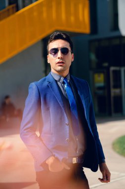 İki renkli kot pantolonlu, siyah beyaz kravatlı ve gözlüklü bir adam..