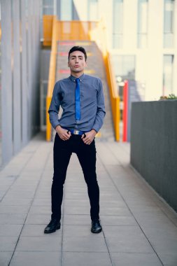 İki renkli kot pantolonlu, siyah beyaz kravatlı ve gözlüklü bir adam..