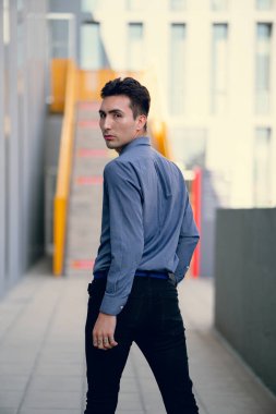 İki renkli kot pantolonlu, siyah beyaz kravatlı ve gözlüklü bir adam..