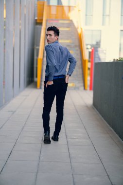 İki renkli kot pantolonlu, siyah beyaz kravatlı ve gözlüklü bir adam..