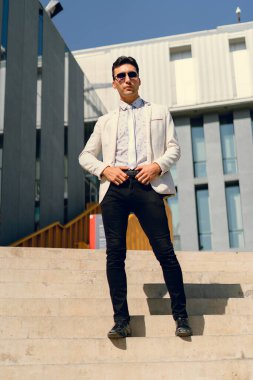 İki renkli kot pantolonlu, siyah beyaz kravatlı ve gözlüklü bir adam..