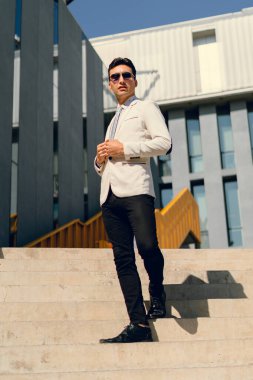 İki renkli kot pantolonlu, siyah beyaz kravatlı ve gözlüklü bir adam..