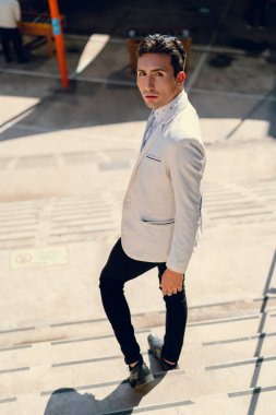 İki renkli kot pantolonlu, siyah beyaz kravatlı ve gözlüklü bir adam..