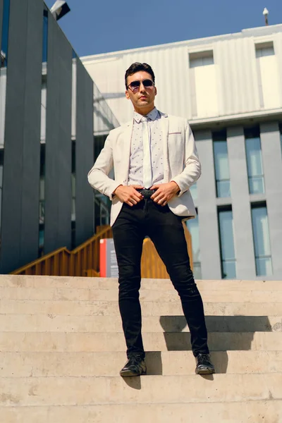 İki renkli kot pantolonlu, siyah beyaz kravatlı ve gözlüklü bir adam..