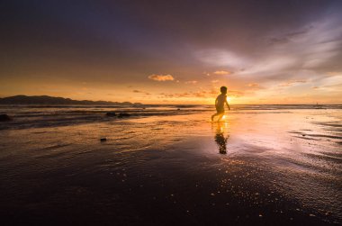 Gün batımında sahilde bir kadının silueti.