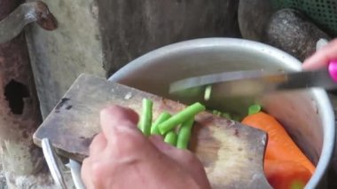 old woman chopping chickpeas on a dirty chopping board in the pan