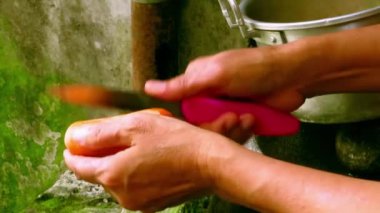 Yaşlı kadın yosunlu ortamda havuç soyarken eline pembe bıçak aldı.