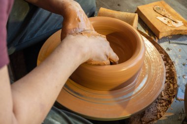 Bir çömlekçinin elleri, çemberin üzerinde toprak kavanozu yaratıyor..