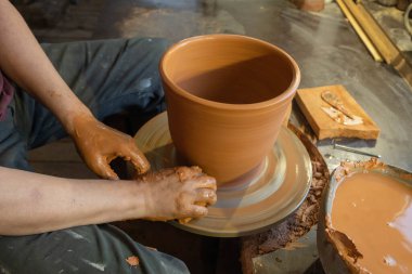 Bir çömlekçinin elleri, çemberin üzerinde toprak kavanozu yaratıyor..