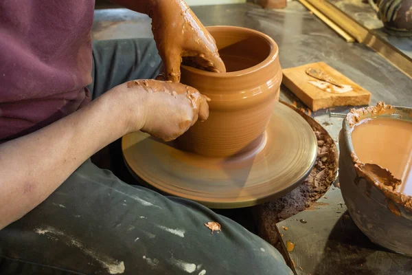 Bir çömlekçinin elleri, çemberin üzerinde toprak kavanozu yaratıyor..
