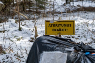 Gübre ormanı, insanlar tarafından atılan çöpler. Siyah mısır. İşaretin üzerinde atık atmayın uyarısı var..