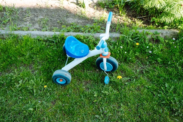 芝生の庭に放置されたプラスチック製の子供用三輪車は — ストック写真