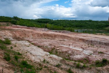 Kırmızı kil ocağı. Kil ocağı. Toprak kayaları inşaat malzemeleri için kazıyor. Karaya güzel bir doğal manzara. Kumlu taş ocağı, kum yükleme, yeraltı suyu.