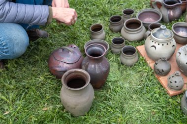 Fırından çıkarılmış toprak eşyalar. Kadın neticeye bakıyor. Kupalar, kaplar, tabaklar ve diğer her şey güzel ve kullanışlı. Letonya Ulusal Kültür Mirası.