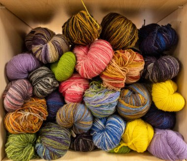 İplik toplarını kapatın. Gökkuşağı renkleri. Örgü örmek için iplik. İplik derileri. Örgü iğneleri, renkli iplikler. Örgü örmek, el yapımı kış kıyafetleri için örgü örmek.