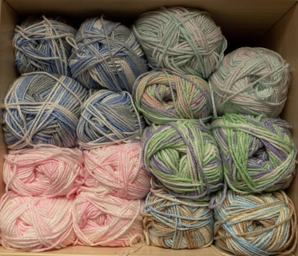 İplik toplarını kapatın. Gökkuşağı renkleri. Örgü örmek için iplik. İplik derileri. Örgü iğneleri, renkli iplikler. Örgü örmek, el yapımı kış kıyafetleri için örgü örmek.