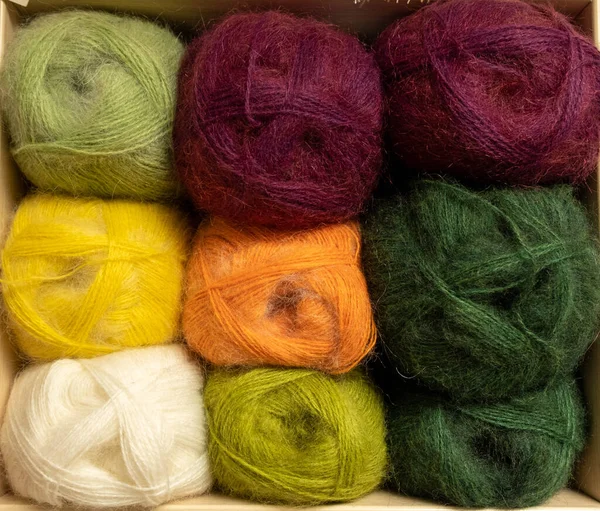 İplik toplarını kapatın. Gökkuşağı renkleri. Örgü örmek için iplik. İplik derileri. Örgü iğneleri, renkli iplikler. Örgü örmek, el yapımı kış kıyafetleri için örgü örmek.