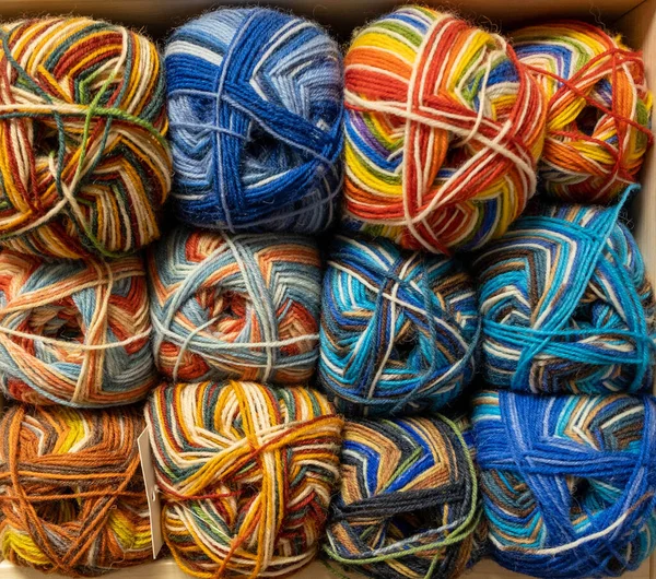 İplik toplarını kapatın. Gökkuşağı renkleri. Örgü örmek için iplik. İplik derileri. Örgü iğneleri, renkli iplikler. Örgü örmek, el yapımı kış kıyafetleri için örgü örmek.