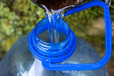 5 litre plastik su şişesiyle doğal kaynak suyu toplamak.