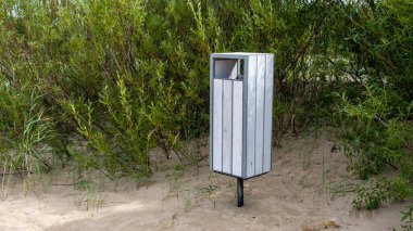 A white garbage container on the Baltic Sea beach. Latvia.