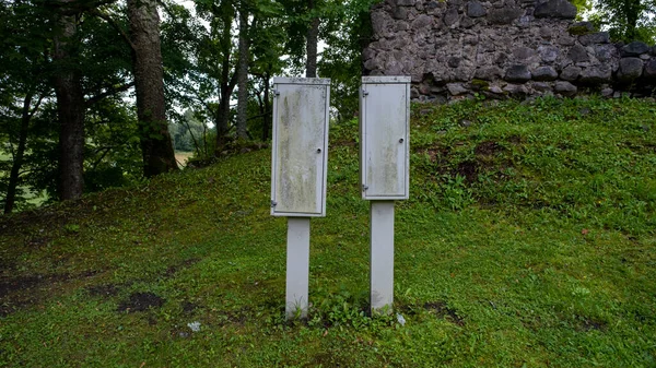 Two white electrical boxes outside, near the castle ruins.