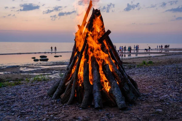 A bonfire on the shore of the Baltic Sea. People at sunset by the sea, Riga Gulf.