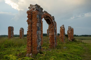 The remains of a stone column from an old building in the middle of a field on a sunny spring day. City Smiltene, Latvia. Old brick stonehenge.