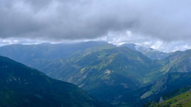 low hanging storm clouds and fog in the mountains on a summer day. blue haze in mountain valleys. it will rain.