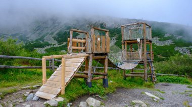 Children's playground equipment high in the High Tatra Mountains. Thick fog at the foot of the mountains, August.