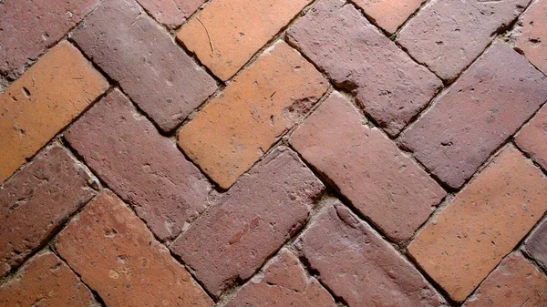 Close up of old brick paved yard, clay brick paving pattern for zigzag style, old paving brick floor is also called brick pavement. Latvian history.