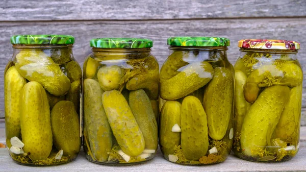 Glass jars with pickled cucumbers. Jars with various pickled vegetables. The concept of canned food in a rustic composition.