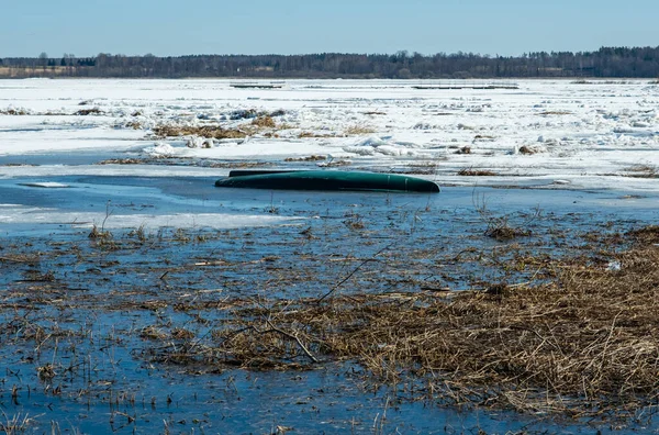 Kısmen donmuş bir gölde eski bir tekne. Tekne karla kaplı..