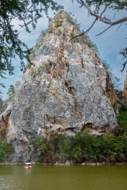 Rock mountain scene and blue sky background. Green botany below the mountain.