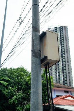 Electric conjunction box attached to the pole. Electrical post by the road with power line cables in the residential area.