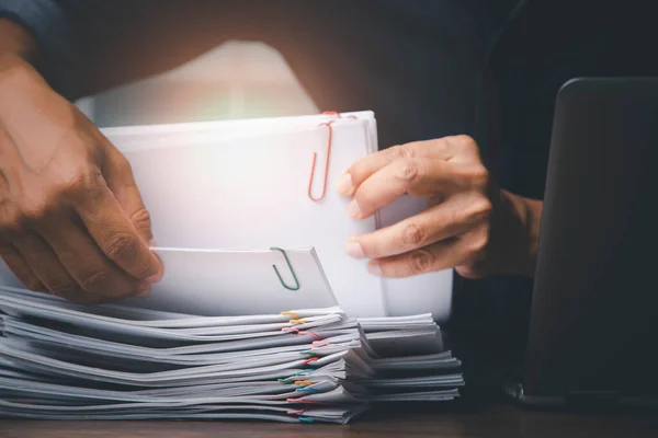 Businessman hand pick up Stack overload documents report papers with colorful paperclip to do data analysis, business and paperless concept.