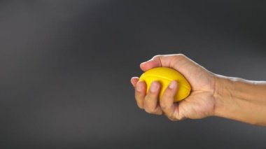 Yavaş çekimde, sarı simülasyon topunu sıkarak, el kaslarını egzersiz sırasında çalıştırır.