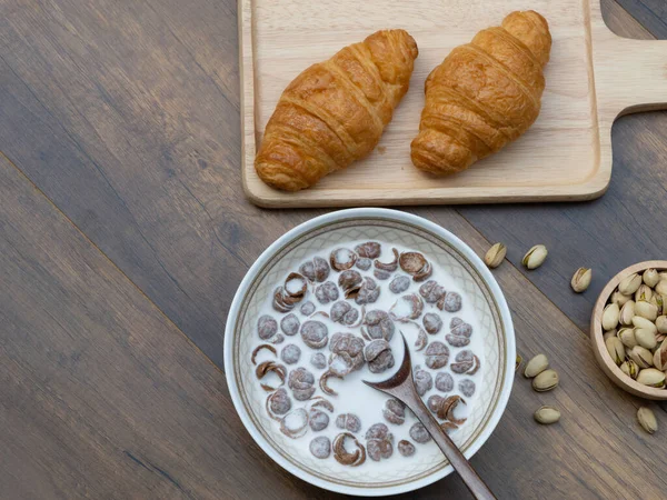 Tahta arka planda süt, kruvasan ve şam fıstıklı mısır gevreğinin fotokopi alanı, sağlıklı gıda konsepti..
