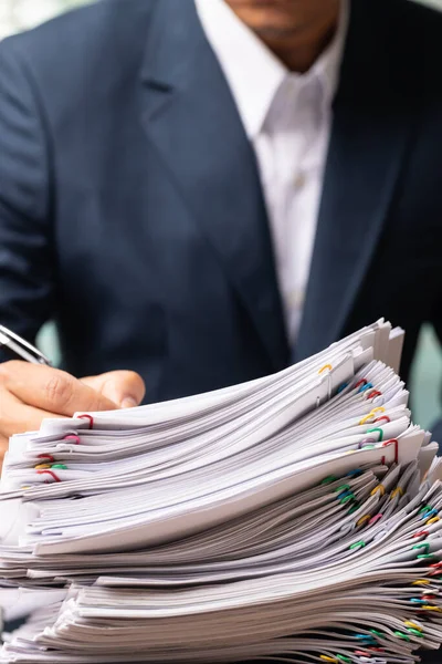 İşadamı dikey olarak açık belge raporu ofis masasında, iş yükleme kağıdı yığını.