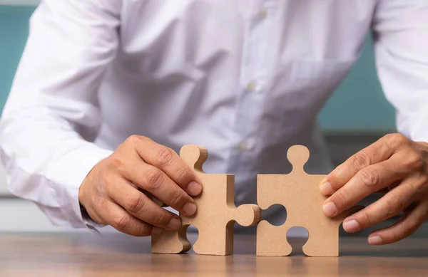 Businessman hand connecting jigsaw puzzle on desk, Business solutions, concept of success and strategy.