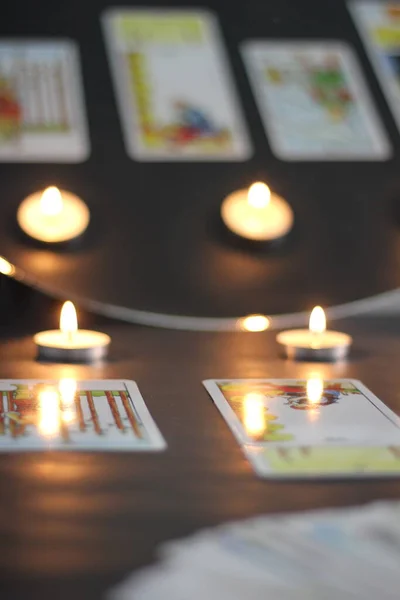 İstanbul, Türkiye - Mart 06 2022: Falcı, kahverengi bir ahşap masada, çay mumlarını yakarken, sıralı tarot kartları okuyor ya da tutuyor.