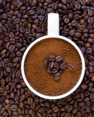 Yerde kahve çekirdekleri ve fincanda taze kavrulmuş kahve.