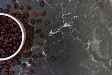 Arka planda bir fincan ve taze kavrulmuş kahve çekirdekleri.